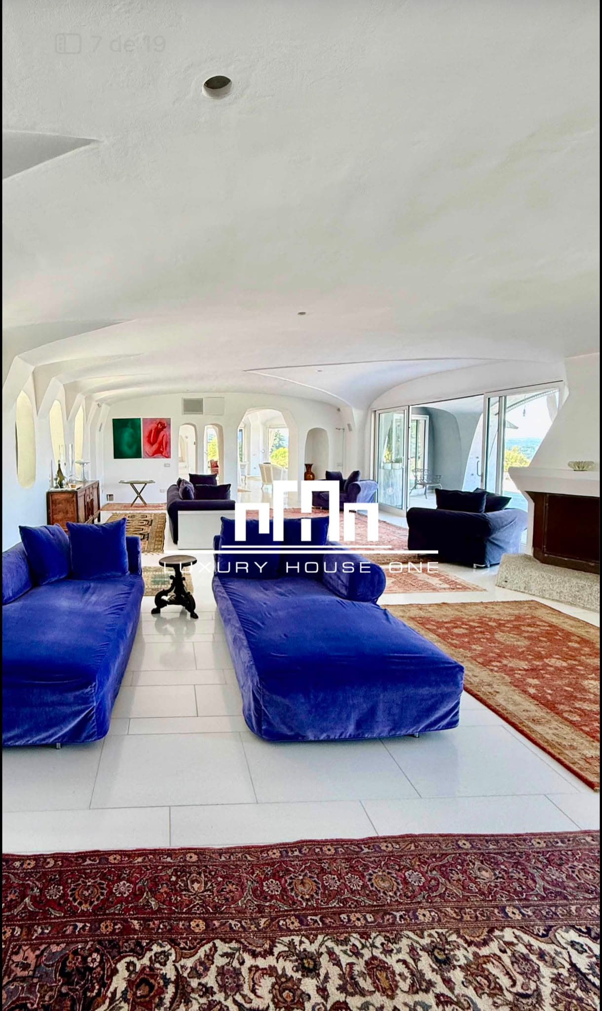 Salone spazioso con divani in velluto blu, pareti bianche curve e tappeti orientali eleganti.